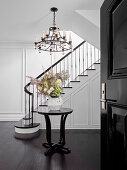 Round table with bouquet of flowers and chandelier in elegant entrance hall