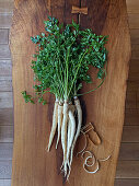 Parsley root with green tops on a wooden surface