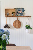 Hook rail with vintage decorations and hanging basket on white beadboard wall