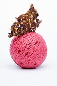A scoop of raspberry-strawberry ice cream with nut brittle