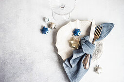Minimalistic table setting for Christmas dinner on white concrete table