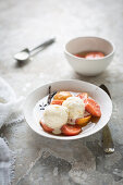 Poached guavas in syrup with ice cream in bowl