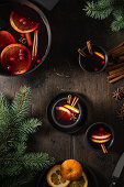 Mulled wine in cups with orange slices on wooden table