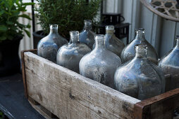 Holztrog mit Vintage Ballonflaschen auf Gartentisch