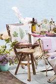 Cushion with botanical print on chair, stool and festively set table by a lake