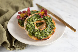 A bagel spread with nasturtium pesto