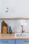 Kitchen unit with grey-blue fronts and white glazed tiles