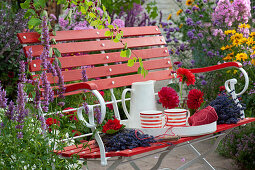 Rote Bank mit Dahlienblüten, Lavendel und Tablett mit Tassen und Krug
