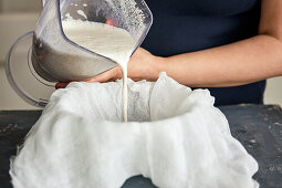 Making almond milk: strain the mixture of ground almonds and water through a gauze cloth