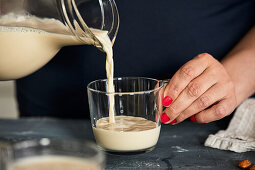 Pouring homemade almond milk into a glass