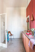Küchenunterschrank, darüber Pendelleuchte vor roter Wand, im Hintergrund weißer, raumhoher Einbauschrank