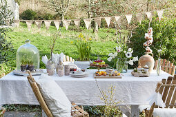 Table set for Easter meal outdoors with pale tablecloth below string of bunting