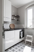 Base unit with high-gloss fronts and cement tiles in small kitchen