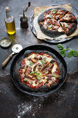 Black pizza with grilled chicken, mushrooms and red onions