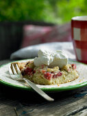 A piece of rhubarb crumble cake with whipped cream