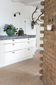 View of white kitchen units with sturdy worktop and brick wall in foreground