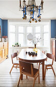 Oval table, chairs, and chandelier with Christmas decoration in a dining room with bay window