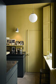 Kitchen with dark furniture and yellow wall