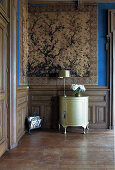 Antique cupboard in a room with large-format tapestry and wood paneling