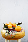 Still life with oranges on a flowered stool
