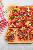 Pizza with tomatoes, red onions, chili, and feta