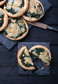 Vegan mini pizzas with spinach, pine nuts, and almond cheese