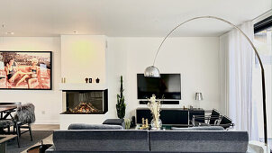 Sofa, arc lamp, TV and fireplace in living area next to dining area