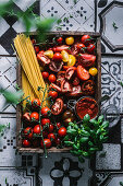 Bunte Tomaten, Pesto Rosso, Spaghetti und Basilikum in rustikaler Holzkiste