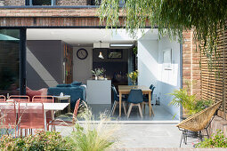 Table and chairs on terrace with view into open-plan interior