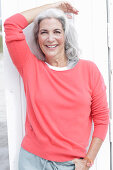 Reife Frau mit grauen Haaren in lachsfarbenem Pullover