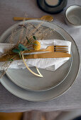 Christmas place setting with dried grass and golden cutlery