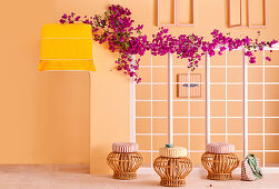 Rattan stools with cushions in front of mullioned windows with bougainvillea