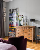 Brass candlesticks and a 1950s table lamp on top of a set of 19th century oak drawers in bedroom