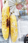 Grilled corn on the cob with salt flakes and melted butter on newspaper