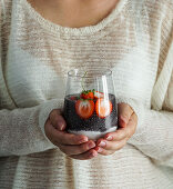 Woman holding glass with chia pudding and yogurt with strawberries
