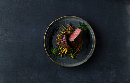 Fillet of beef with julienne cut vegetables on dark stone background
