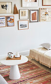 A side table with a conical base on an ethnic rug in front of a picture gallery