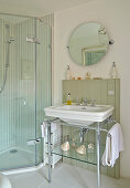 sink with metal frame and round pivot mirror next to a stand up shower