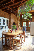 Dining area in open plan room with creek stone walls and tree