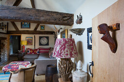 Artworks on walls of rustic living room with wooden beams and antique wooden shoe last mounted on door