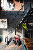 Wrought iron stove under metal stairs in room with black painted brick wall