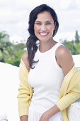 Dark-haired woman in white top and yellow cardigan