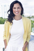 Dark-haired woman in white top and yellow cardigan