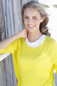 A young blonde woman wearing a white top and a yellow jumper