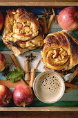 Sweet apple sticky cinnamon rolls buns with coffee mug, gardening apples and cinnamon sticks