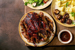 Holiday Thanksgiving table with classic dishes roasted glazed duck with apples, boiled potatoes, green salad and sauce