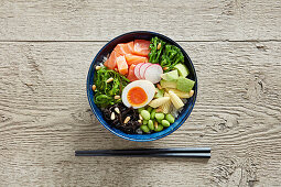 Poke bowl with rice, salmon, seaweed, vegetables and egg