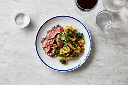 Thinly sliced beef served with vegetable salad with kale, cauliflower, and chickpeas