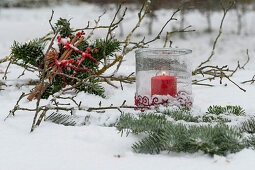 Stern aus Tannenzweigen und Windlicht im Schnee