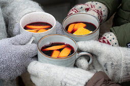 Hands with gloves toast with mulled wine